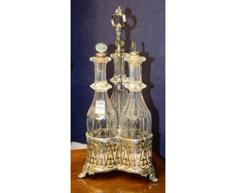 An early 20th century plated bottle stand, the scroll handle with shell motif, above stem support, ending in pierced ornate d