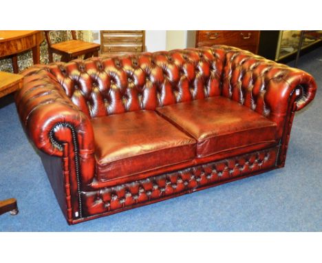 A Chesterfield ox blood two seater settee, with button back and cushion arms, 60cm high x 163cm wide