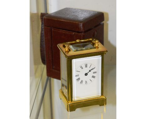 A brass carriage clock, with carry handle and white enamel dial with Roman numerals, with leather tooled carry case, 11cm hig