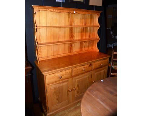 A pine Ercol kitchen dresser, with shelved plate rack above three small drawers and three panelled doors, 169cm high x 135cm 