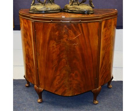 A mahogany commode cabinet, with shaped top above panelled door enclosing shelved interior, raised on short cabriole supports