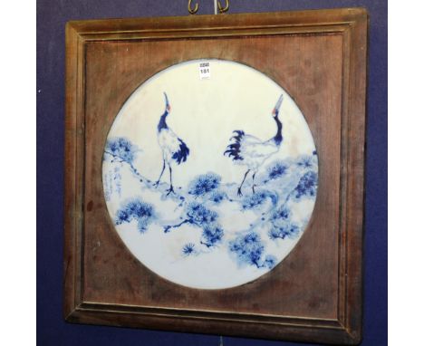 A Chinese blue and white ceramic wall panel, depicting storks in foliage, with character marks on white ground, in wooden fra
