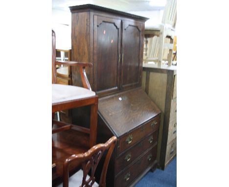 A GEORGIAN OAK WRITING BUREAU, with cupboard above the fall front revealing various pigeon holes and drawers above three long