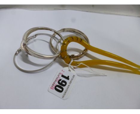 FOUR WHITE METAL BANGLES, together with a hair comb