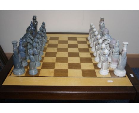 A LLADRO PORCELAIN CHESS SET, with board, thirty two pieces of Medieval design by Julio Fernadez, retined in 1985
