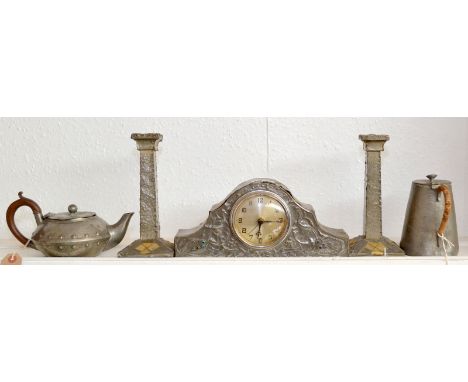 An Arts and Crafts pewter clad small mantle clock decorated with peacocks, their tails with enamelled jewelling together with
