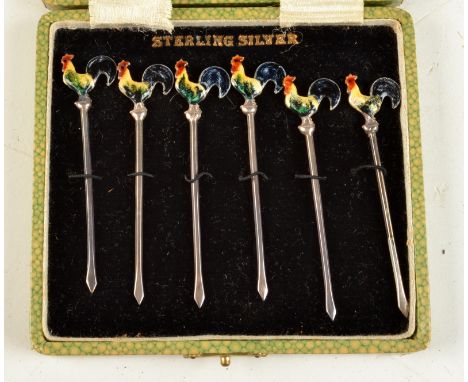 A set of six silver cocktail sticks, the finial of each in the form of an enamelled cockerel, cased. 