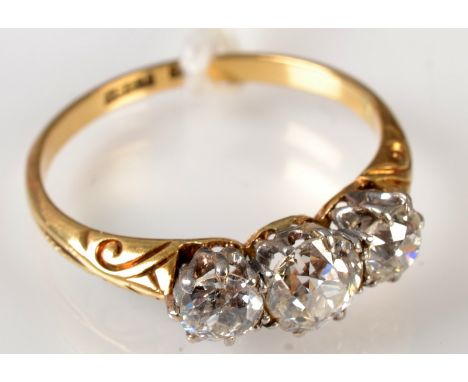 An 18ct yellow gold three stone diamond ring with scroll chased shoulders, the central old cut diamond of approximately 0.5ct