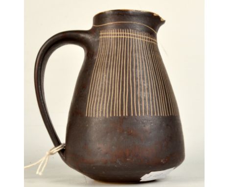 A Lucie Rie sgraffito cream jug, manganese glaze, white interior, height 11.5cm.  Condition report: Several chips to spout. T