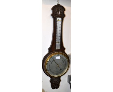 An aneroid barometer/thermometer on a carved oak mount. 