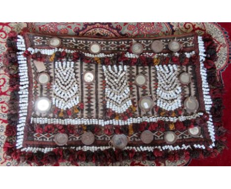 A persian flatweave camel bag, decorated with small metal surround mirrors, porcelain beads and mother of pearl buttons, comp