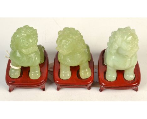 A set of three jade Dogs of Fo on hardwood stands, each height excluding stand 6.5cm. 