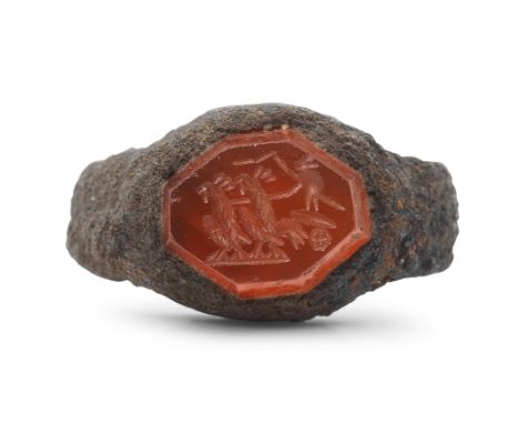  A Roman iron and carnelian intaglio ring with cockerels pulling a chariot Circa 2nd-3rd Century A.D.The iron band set with a