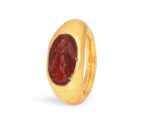  A Roman gold and carnelian intaglio ring  Circa 1st Century A.D.Engraved with winged Eros standing leaning on an extinguishe