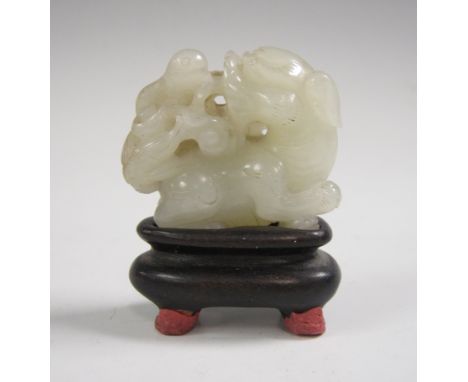 A small Qianlong carved jade Dog of Fo with lotus flower, on small wooden stand, 1in H