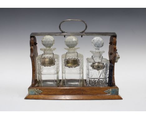 Silver plated oak Tantalus, 38 x 31cm, with three glass decanters, two silver decanter labels, and one white metal whisky lab