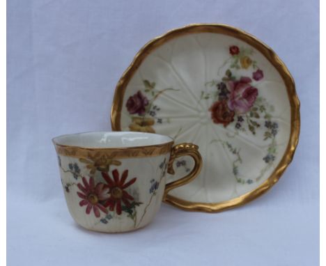 A Royal Worcester porcelain tea cup and saucer, transfer and infill decorated with flowers and leaves to an ivory ground, puc