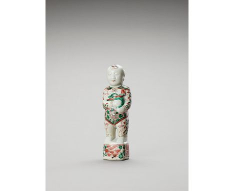   A FAMILLE VERTE PORCELAIN FIGURE OF A BOY  China, Kangxi period (1662-1722). Standing on a rectangular base, wearing floral