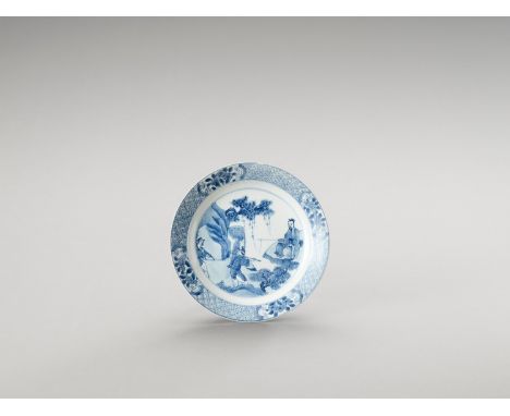   A BLUE AND WHITE PORCELAIN DISH  China, Kangxi period (1662-1722). The dish is decorated on the show side with an outdoor s