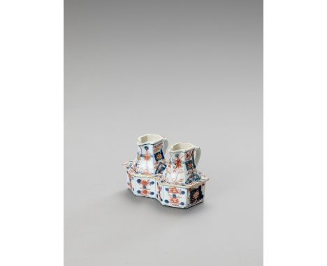   A PAIR OF IMARI PORCELAIN JUGS WITH ORIGINAL HOLDER  China, Kangxi period (1662-1722). Consisting of two small hexagonal ja