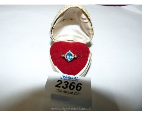 A pretty 9ct gold ring set with central pale blue stone surrounded by small diamonds in diamond format and diamond to shoulde