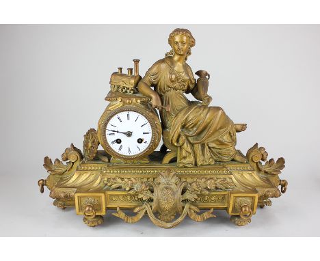 A French gilt metal figural mantel clock, drum case with circular dial and Roman numerals, decorated with a seated figure bes