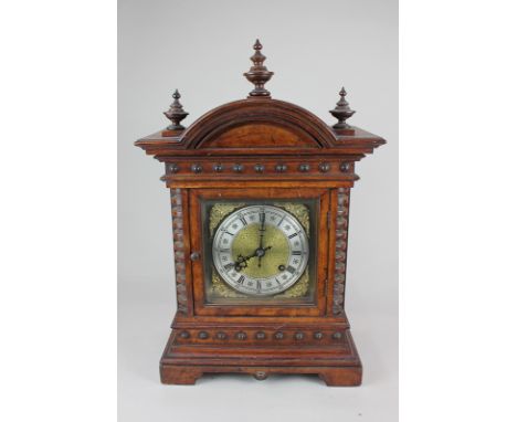 A walnut cased mantel clock, the brass face with cherub spandrels, the silverised dial with Roman and Arabic numerals, the mo