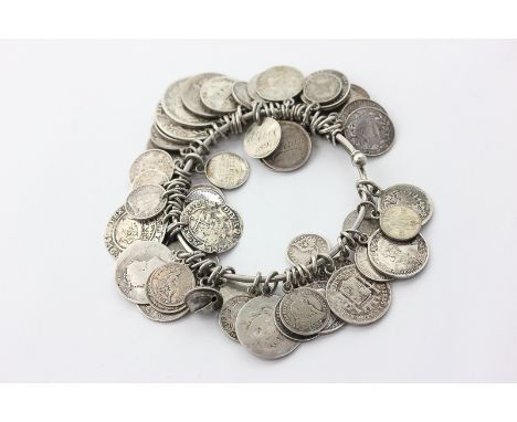 A silver bangle hung with a large number of various silver coins