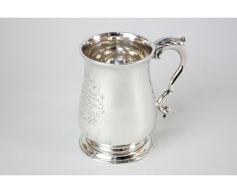 A George III silver mug, baluster shape on circular foot with leaf capped scroll handle, with presentation inscription in lau