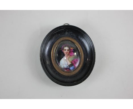 An oval miniature portrait of a lady in European dress, wearing a pink headscarf, one hand raised to her face, 4.5cm by 3.6cm