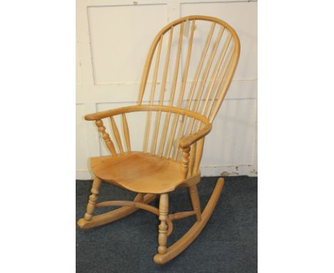 A comb back Windsor rocking chair by Robin Clarke Windsor Chairs of Leominster with hoop arms and solid dished seat, on turne