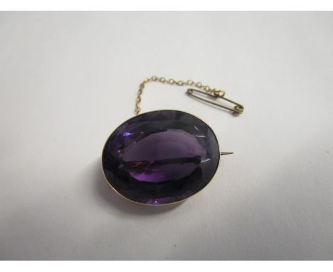 A yellow gold coloured set oval amethyst brooch on safety chain 