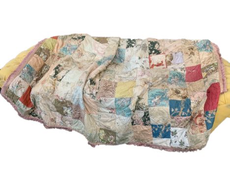 An early 20th century quilt, with panels of antique fabric, each panel topstitched with fine chain stitch, pink fringe around