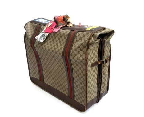 A vintage Gucci garment carrier travel trunk, in double G monogram canvas and leather, unfolds to reveal single hanging compa