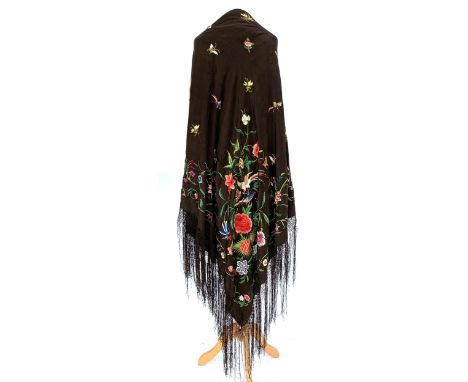 An early 20th century black silk piano shawl, profusely embroidered with exotic birds, flowers, and butterflies, with knotted