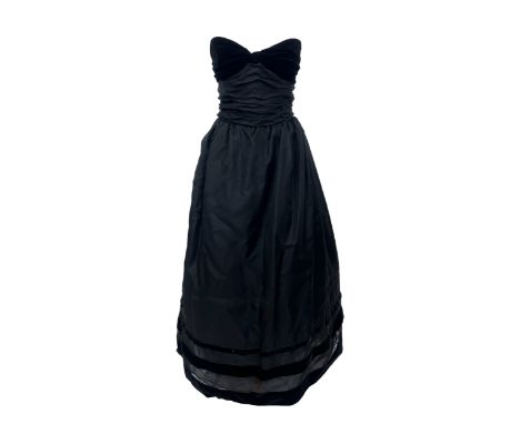 A Bellville Sassoon black strapless gown, the boned bodice in ruched black silk chiffon with velvet bow detail bust, the volu