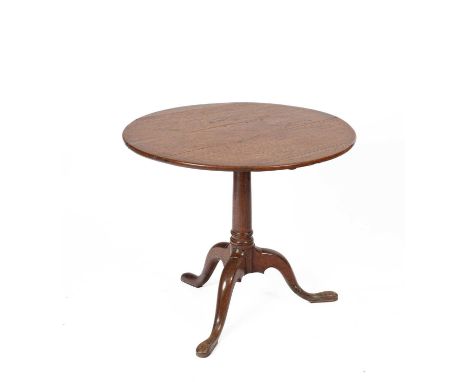 A George III oak circular tilt top tripod table the circular top raised on a gun barrel column with tripod legs terminating i