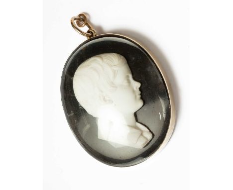 An oval memorial cameo pendant, 19th Century, carved portrait of a young boy with hair scroll to reverse, in a gold coloured 