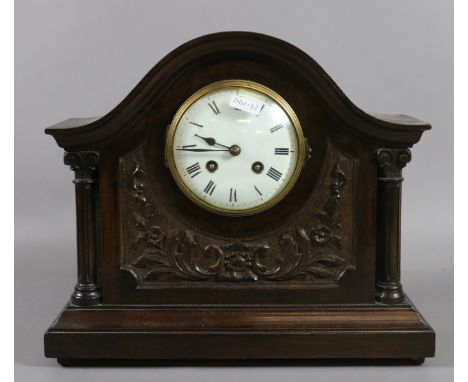 A carved mahogany mantel clock, enamel dial with Roman numerals flanked by two turned columns chiming on a coiled gong.
