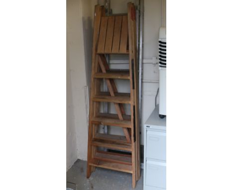 Three old pairs of step ladders; two wooden, one metal.