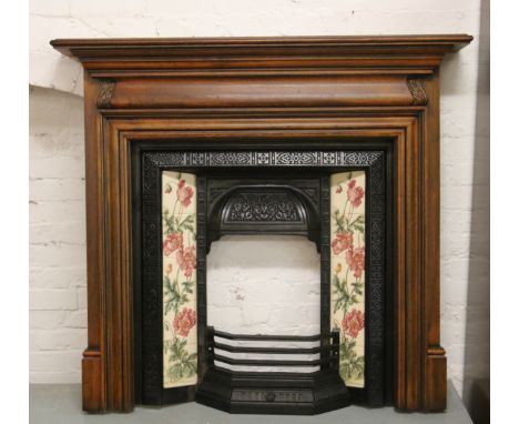 A carved mahogany fire surround along with a cast iron insert set with decorative tiles.