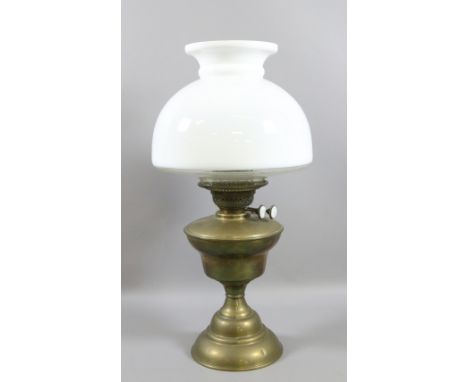 A brass based oil lamp with opaque glass shade.