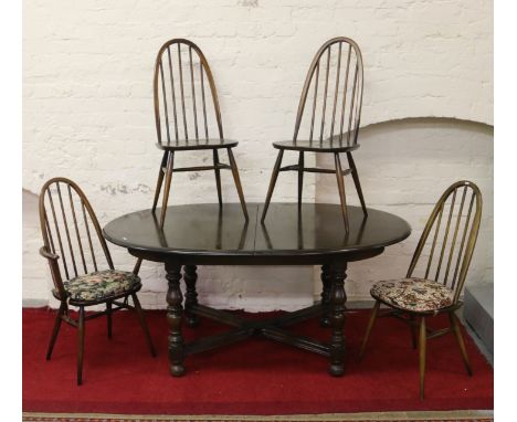 An Ercol dark oak oval extending dining table raised on turned supports along with a set of  Ercol three plus one carver spin