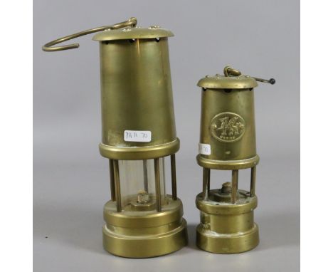 A brass cased miners lamp along with a smaller brass miners lamp.