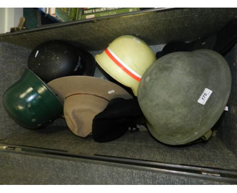 A black trunk containing a number of military and other helmets including a Nazi style example