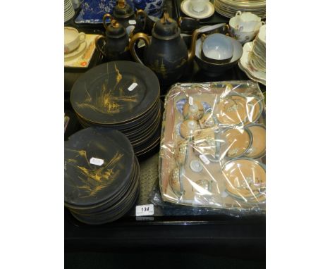 A Japanese part tea service decorated with gilt landscapes on a blackground, to include tea pot, milk jug, sugar bowl, cups a