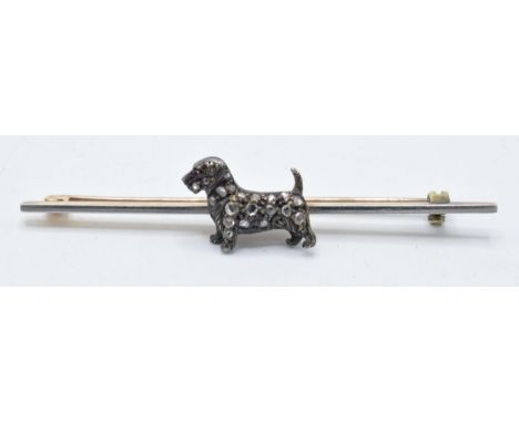 A novelty diamond set dog brooch with old cut / rose cut diamond body with ruby eye set on 9ct gold bar brooch setting, 58mm 
