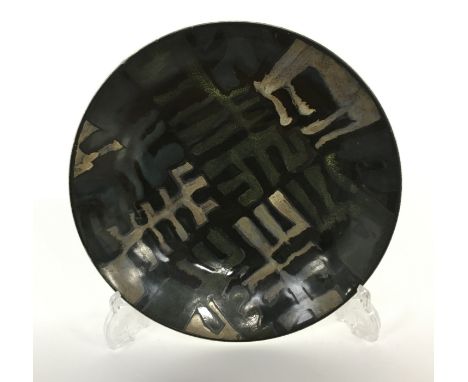 A Poole Pottery Studio dish in an Abstract design in dark glazes on a black ground (10 inches diameter).