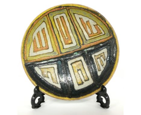 A Poole Pottery Studio dish in an Abstract design in early textured glazes by Geraldine O'Meara (8 inches diameter).