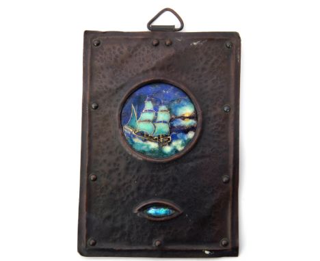 Arts &amp; Crafts metal plaque with planished finish, the centre inset with an enamel plaque of a galleon with further small 